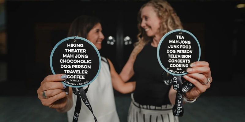 two women holding conference badges with a list of personal interests
