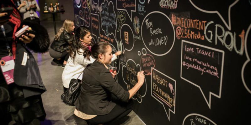 a large wall with two women writing messages on it with chalk